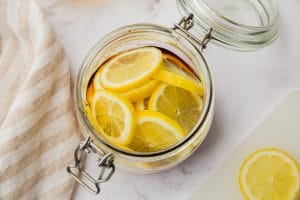 sliced lemons in clear jar with some brown honey