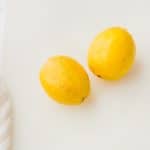 two lemons on white cutting board