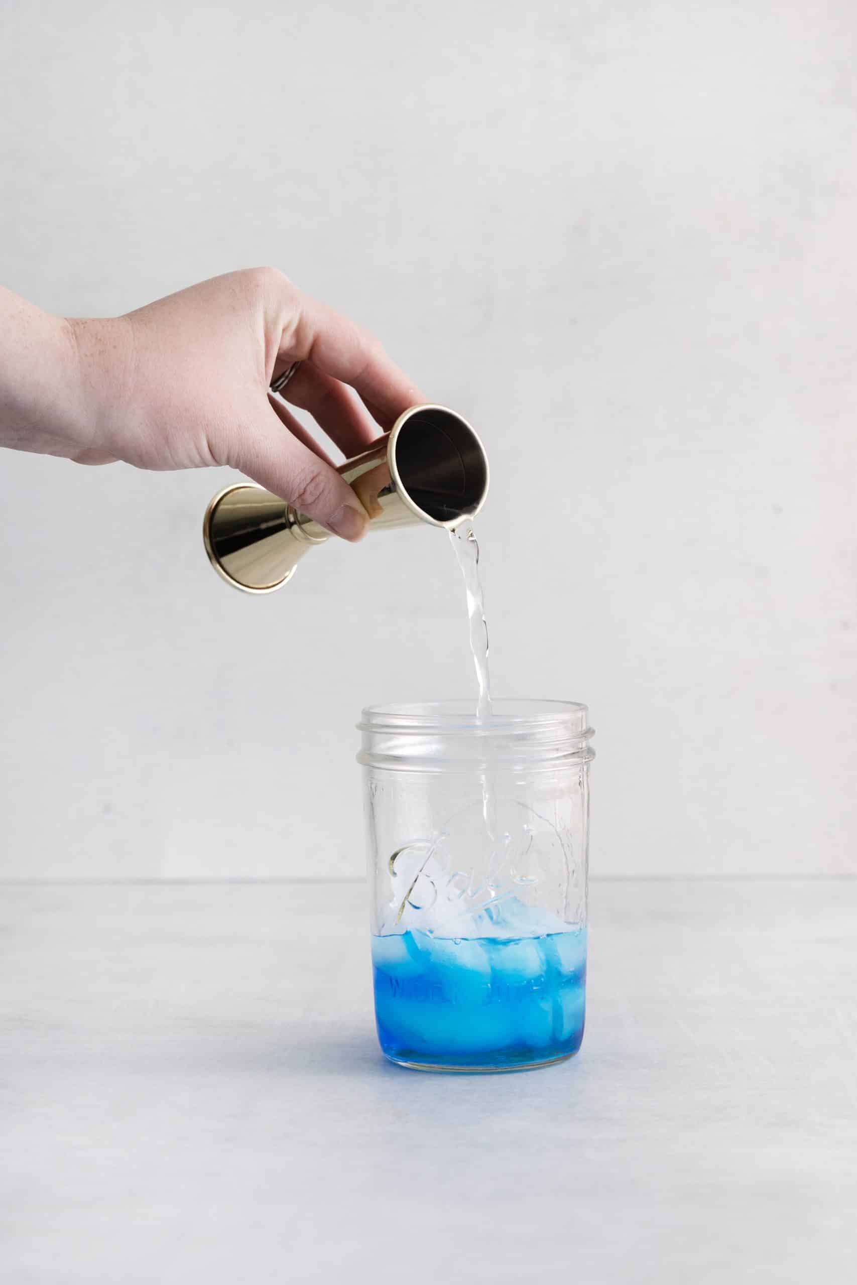 clear liquid being poured into a ball jar with blue liquid