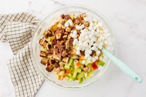 glass bowl with ingredients: marshmallow, snickers, apple chunks