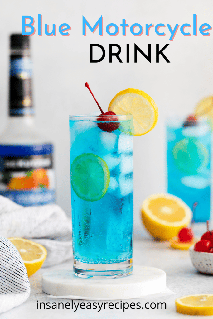tall clear glass with blue liquid and ice cubes A lemon wheel on top and a cherry with text overlay, blue motor cycle drink