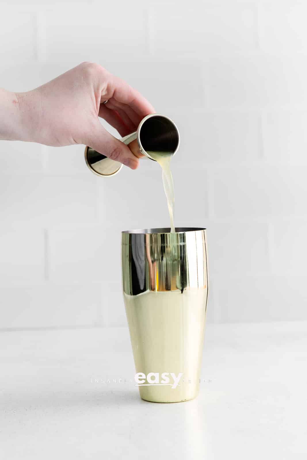 liquid being poured into golden drink shaker