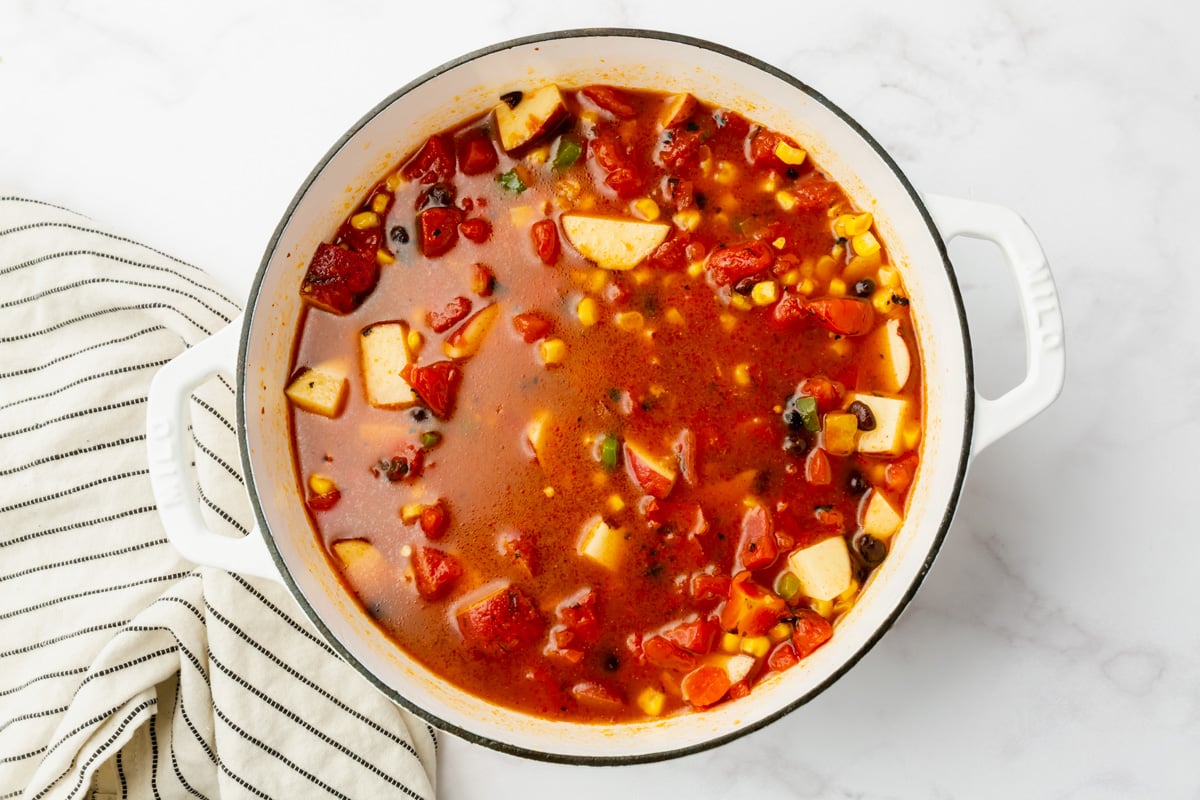 pot filled with red sauce, corn, tomatoes, potatoes