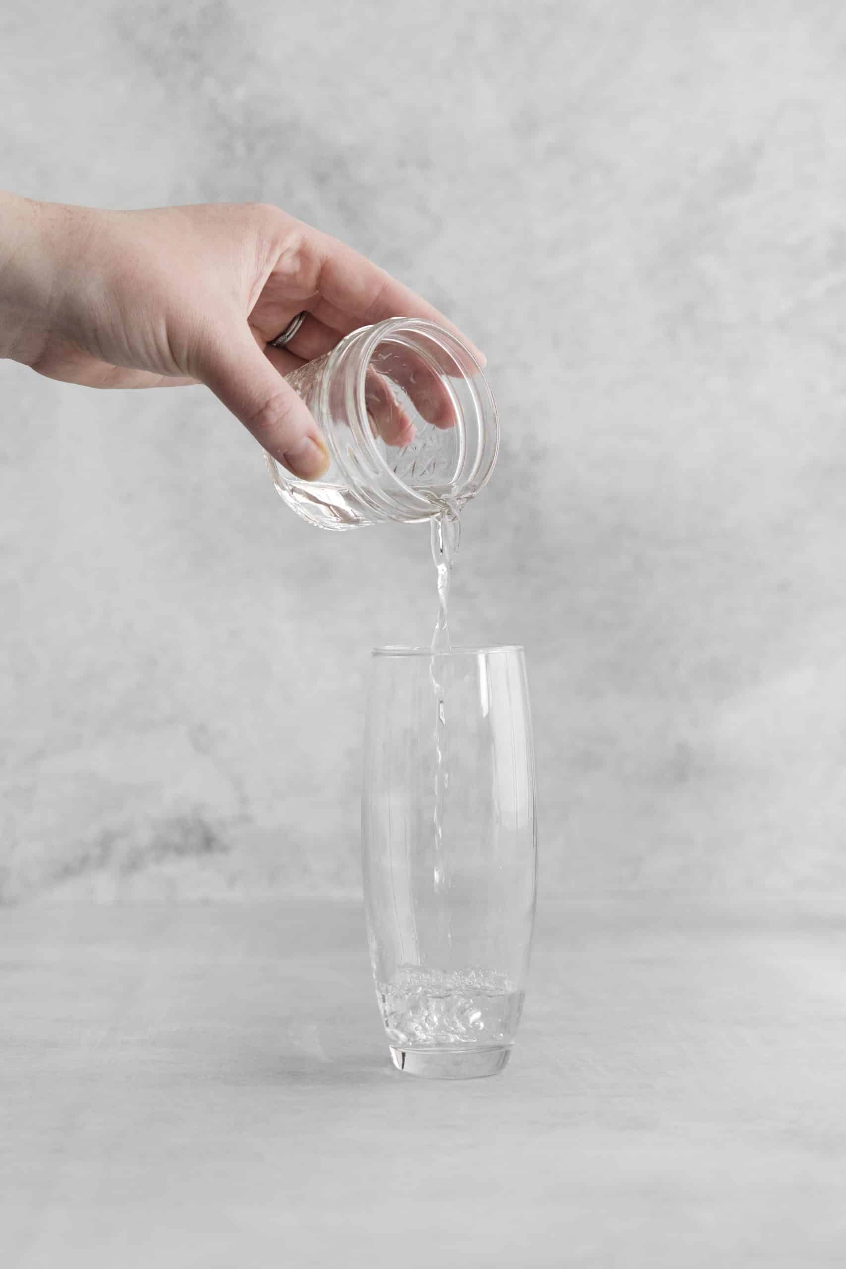 clear liquid being poured into a clear tall glass