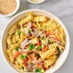 leftover turkey pasta bake in a white dish in a white bowl, you can see turkey, pasta, veggies and cheese, two bowls of parm and panko to top let