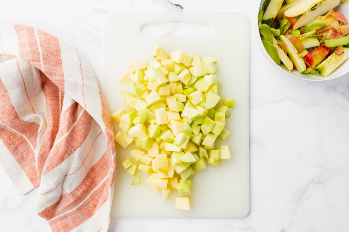 green apples diced on a white cutting board