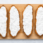 top view photo of 4 toasted sourdough bread slices with yogurt spread on top, on a wooden cutting board