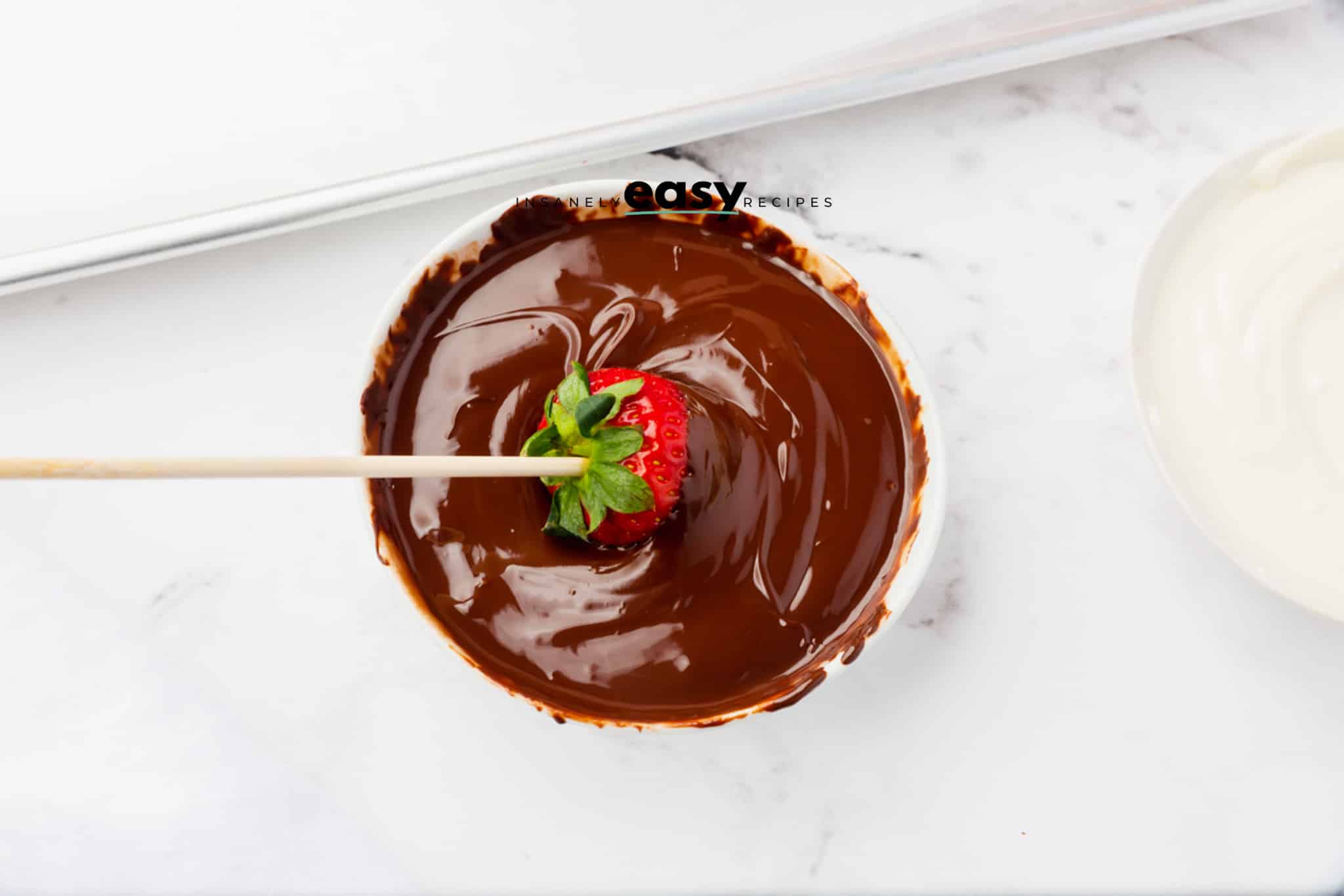 melted chocolate bowl with strawberry being dipped in