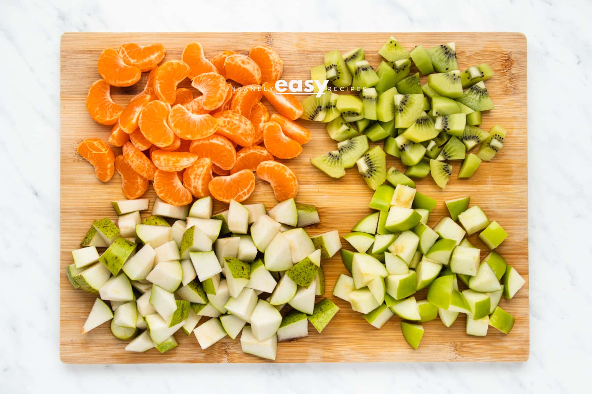 diced oranges and apples and kiwi on cutting board