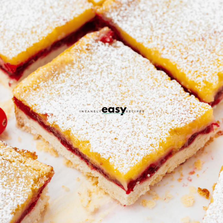 photo of sliced cranberry lemon bars on parchment paper, with other slices surrounding it