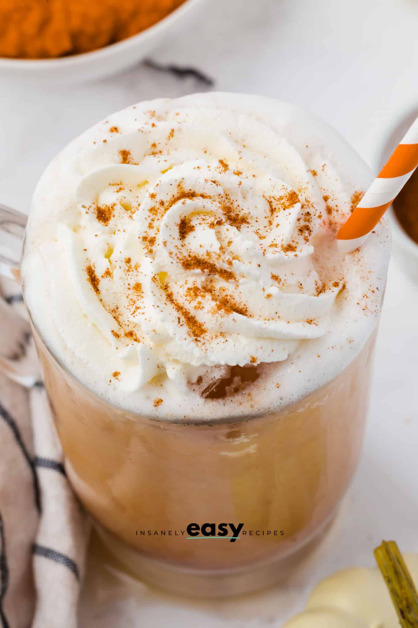pumpkin spice latte over iced with whipped cream and cinnamon sprinkled on top
