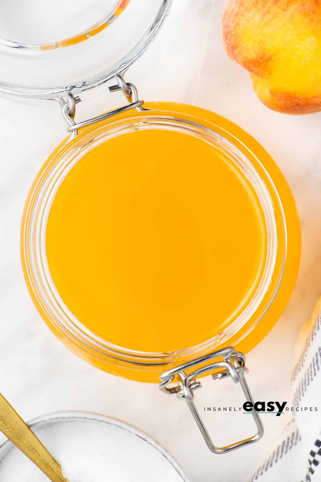 top view photo of peach simple syrup in a glass jar with the lid opened