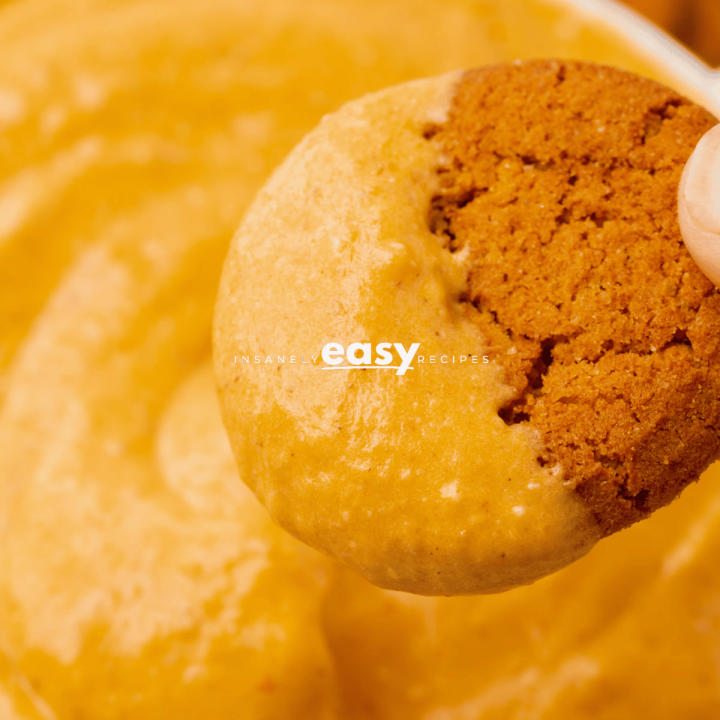 close up shot of pumpkin cream cheese dip and gingersnap cookie being dipped into the dip