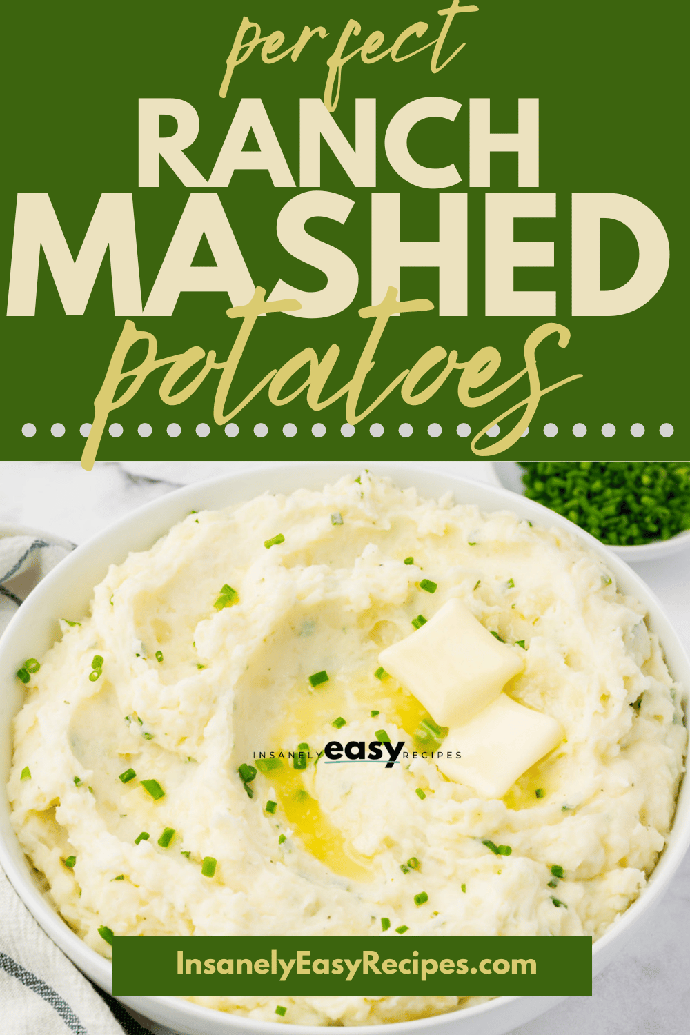 creamy ranch mashed potatoes in a white bowl. Potatoes have green seasoning on top and two butter pads with textoverlay perfect ranch mashed potatoes