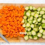 cut carrots and brussels on a wooden cutting board