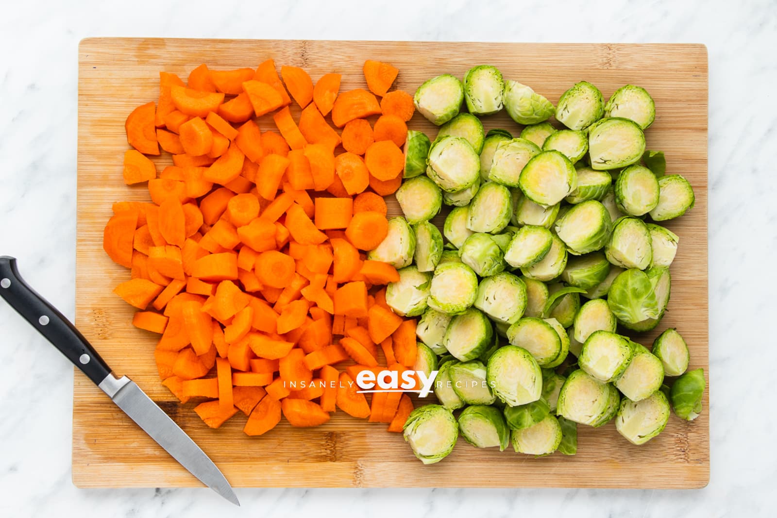 cut carrots and brussels on a wooden cutting board