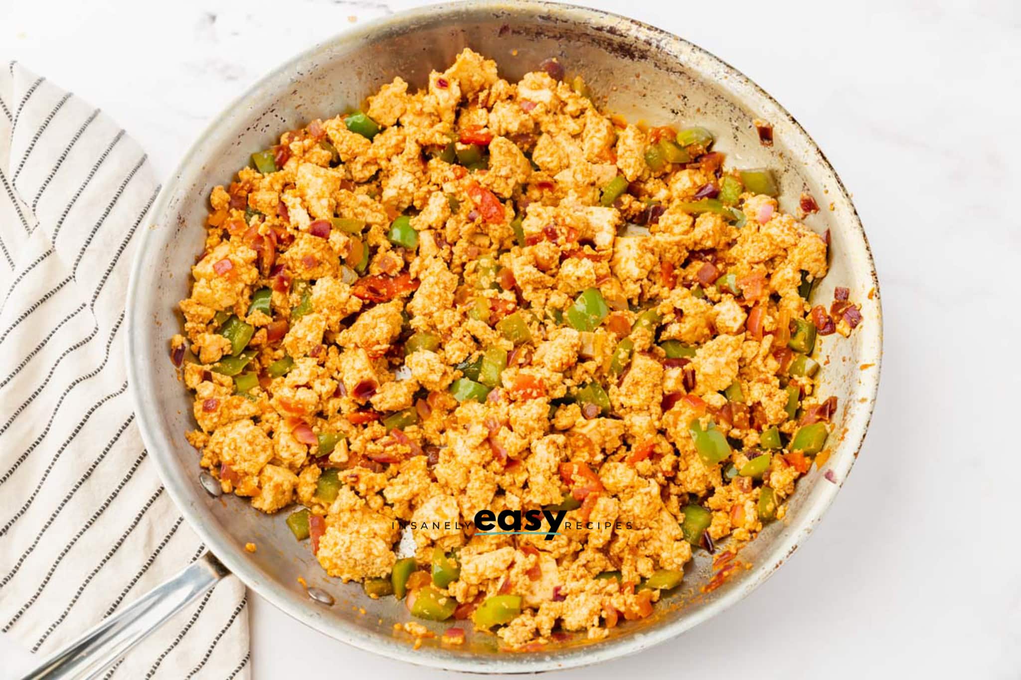 metal skillet with onions and green peppers, tofu crumbles, spices and salsa all mixed together