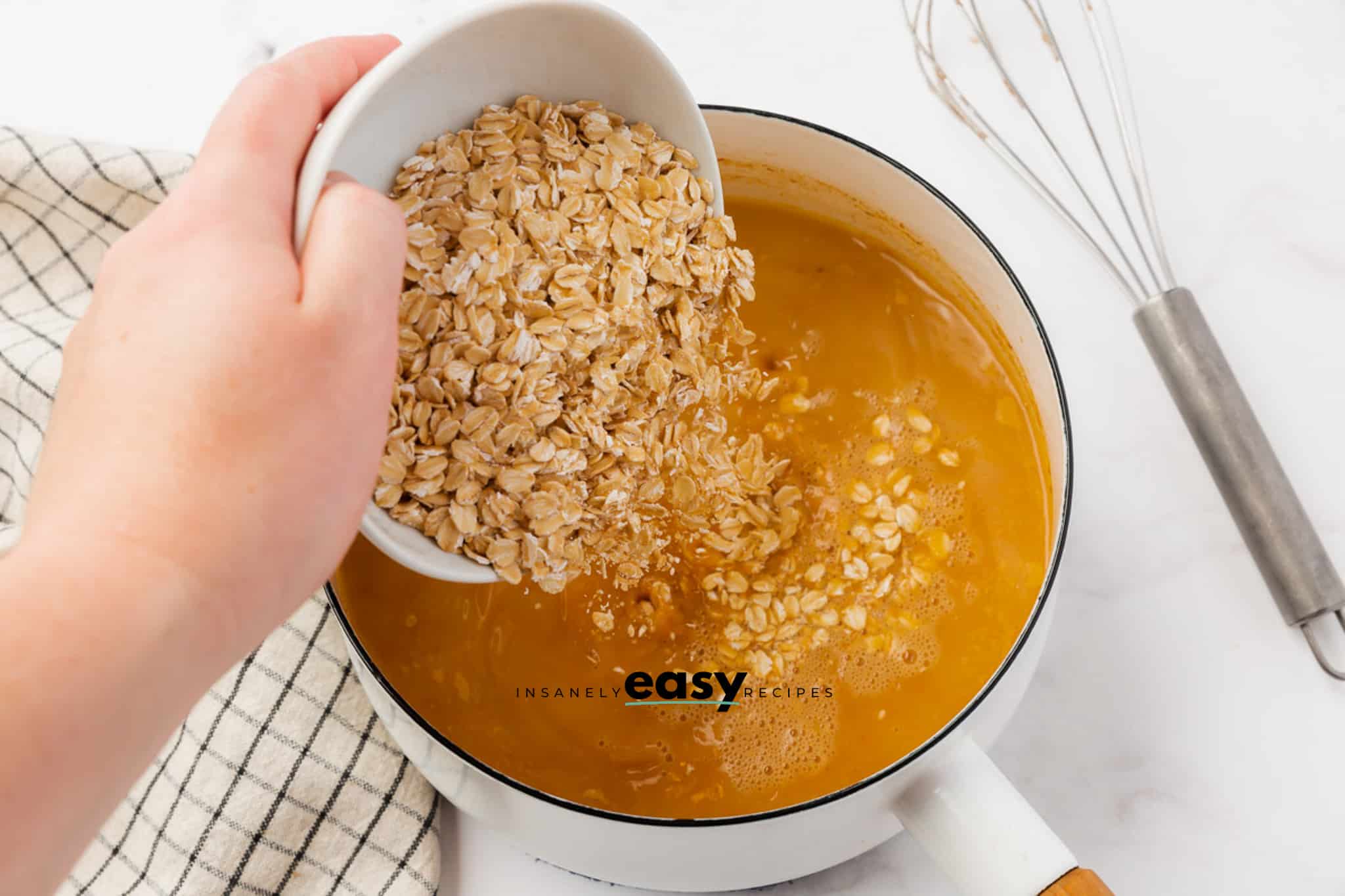 A bowl of oats being added to pumpkin spiced hot milk.