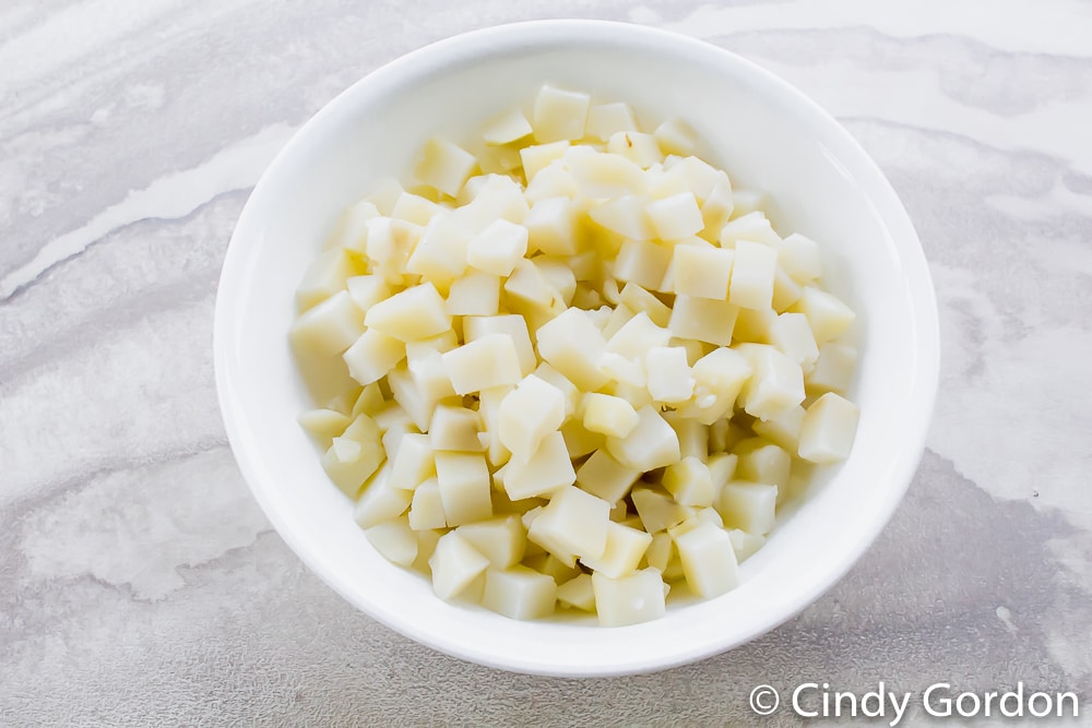 a white bowl filled with cooked cubed potatoes