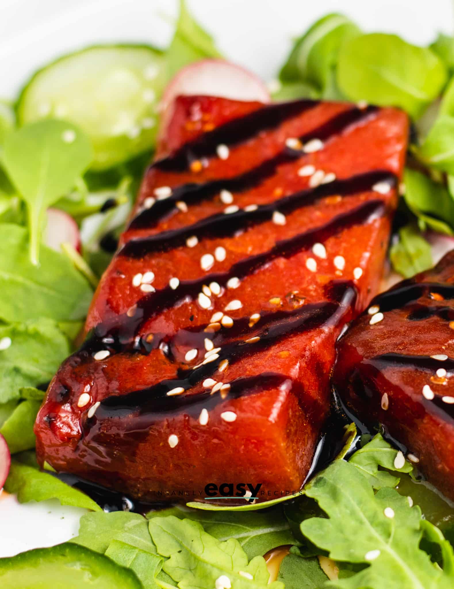 Closeup of a rectangular watermelon steak drizzled with soy sauce and topped with sesame seeds