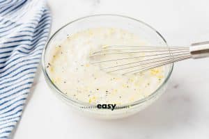 a glass bowl with lemon garlic aioli being whisked together.