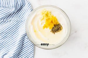 lemon, garlic, and seasonings added to mayo in a glass bowl