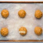 Top view photo of Vegan Pumpkin Cookie dough, formed into six balls, and spread out on a cookie sheet lined with parchment paper.