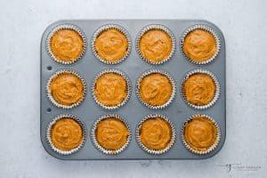 Topview photo of vegan pumpkin muffin batter in a muffin tin, ready to bake.