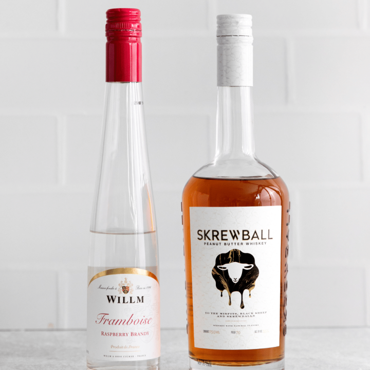 Photo of a bottle of Screwball Peanut Butter Whiskey and a bottle of Framboise Raspberry Brandy.