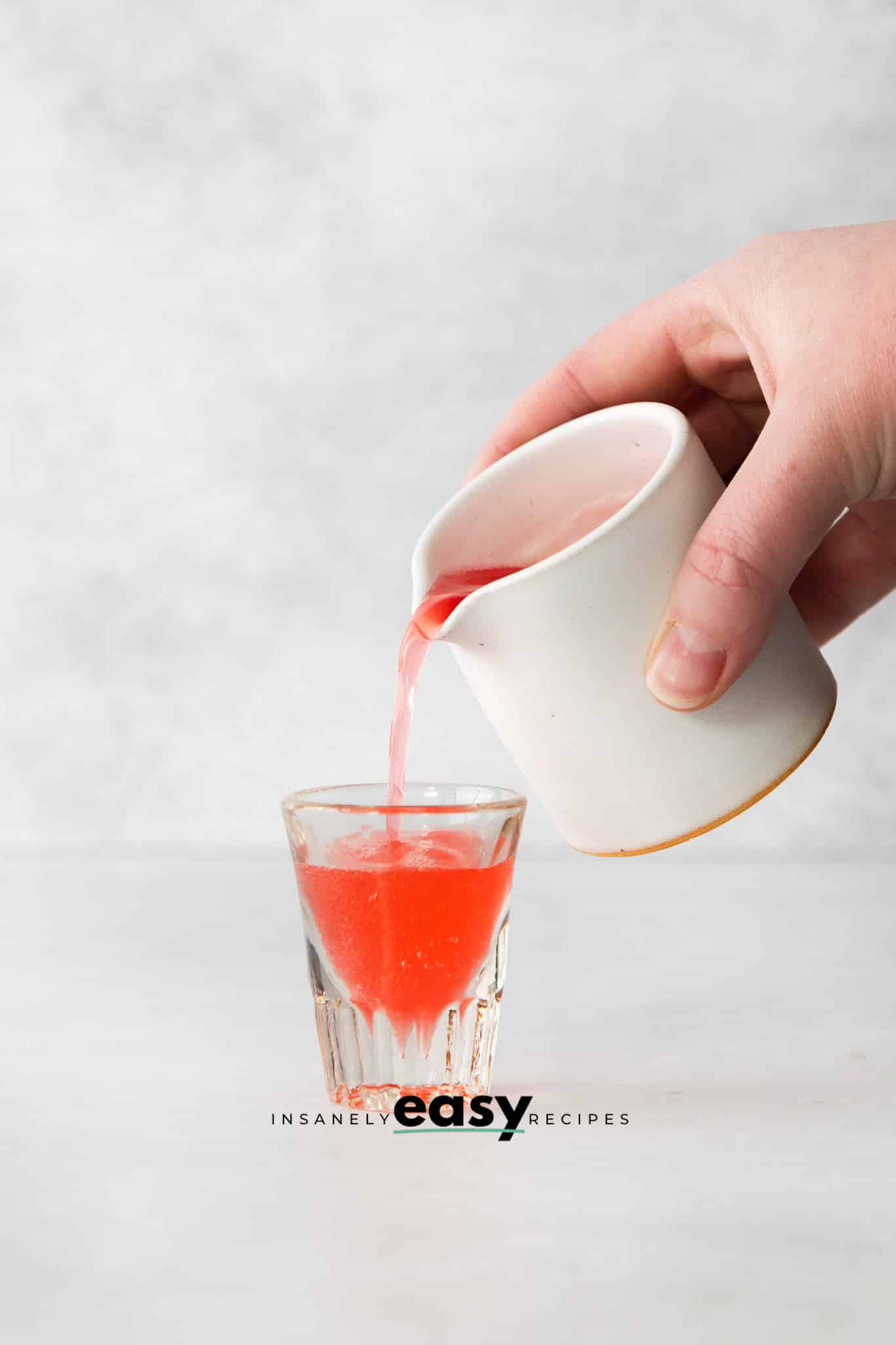 red liquid being poured into shot glass