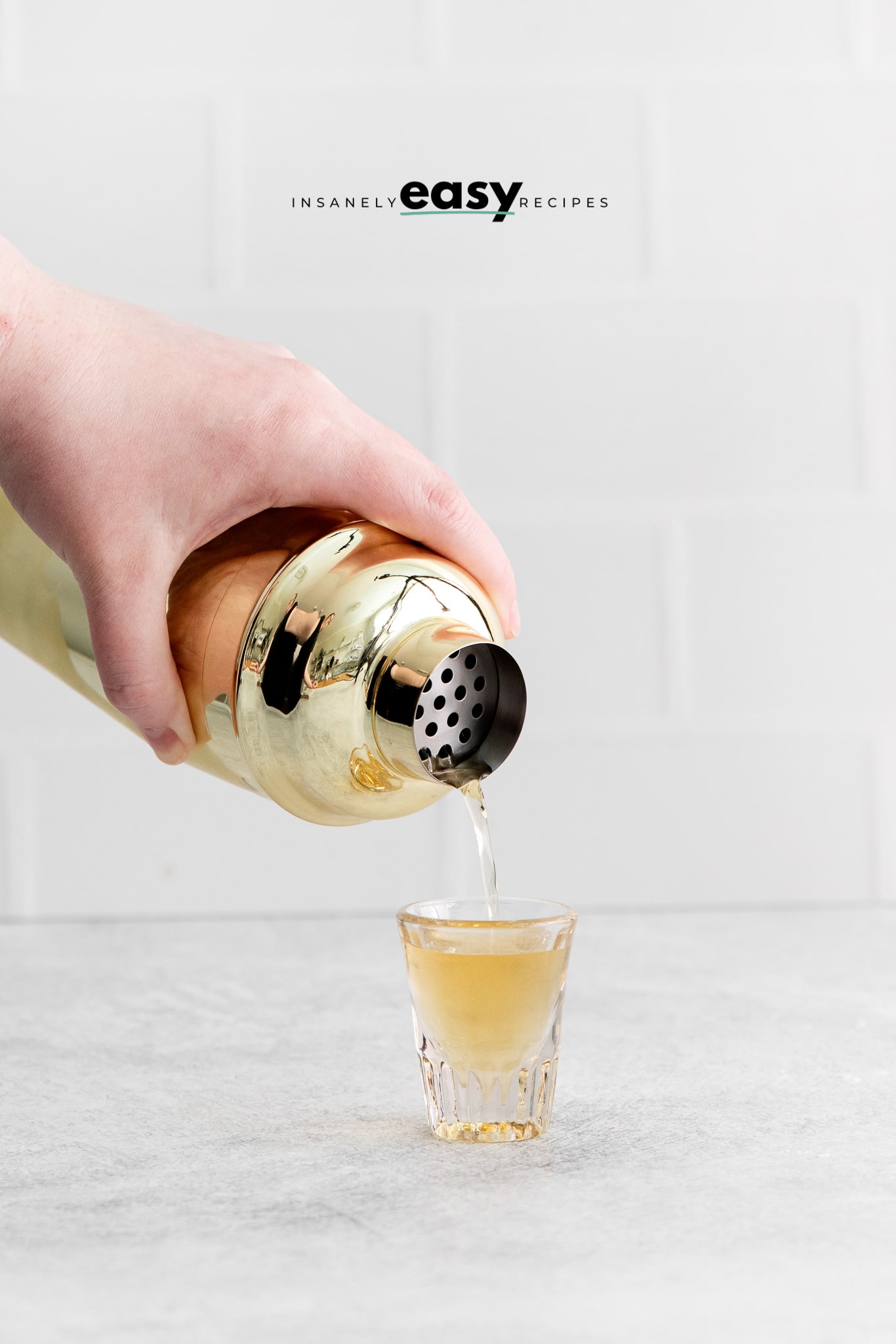 Photo of a hand pouring our a shaken up Peanut Butter Jelly Shot into a shot glass.