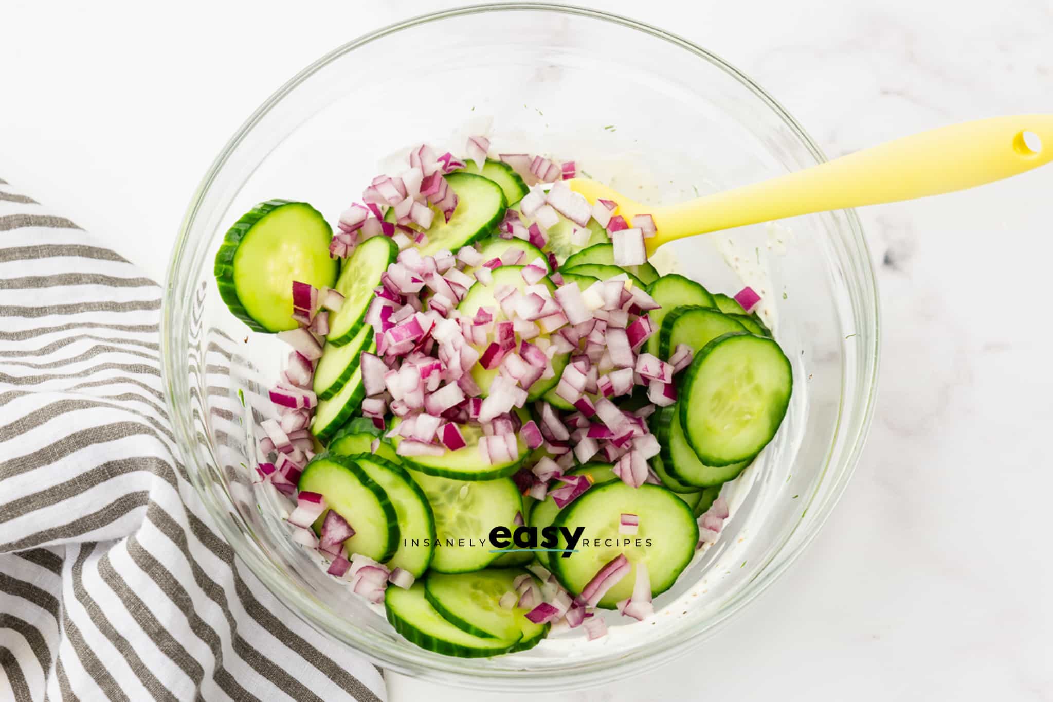 Sliced cucumbers and red onions added to sour cream.