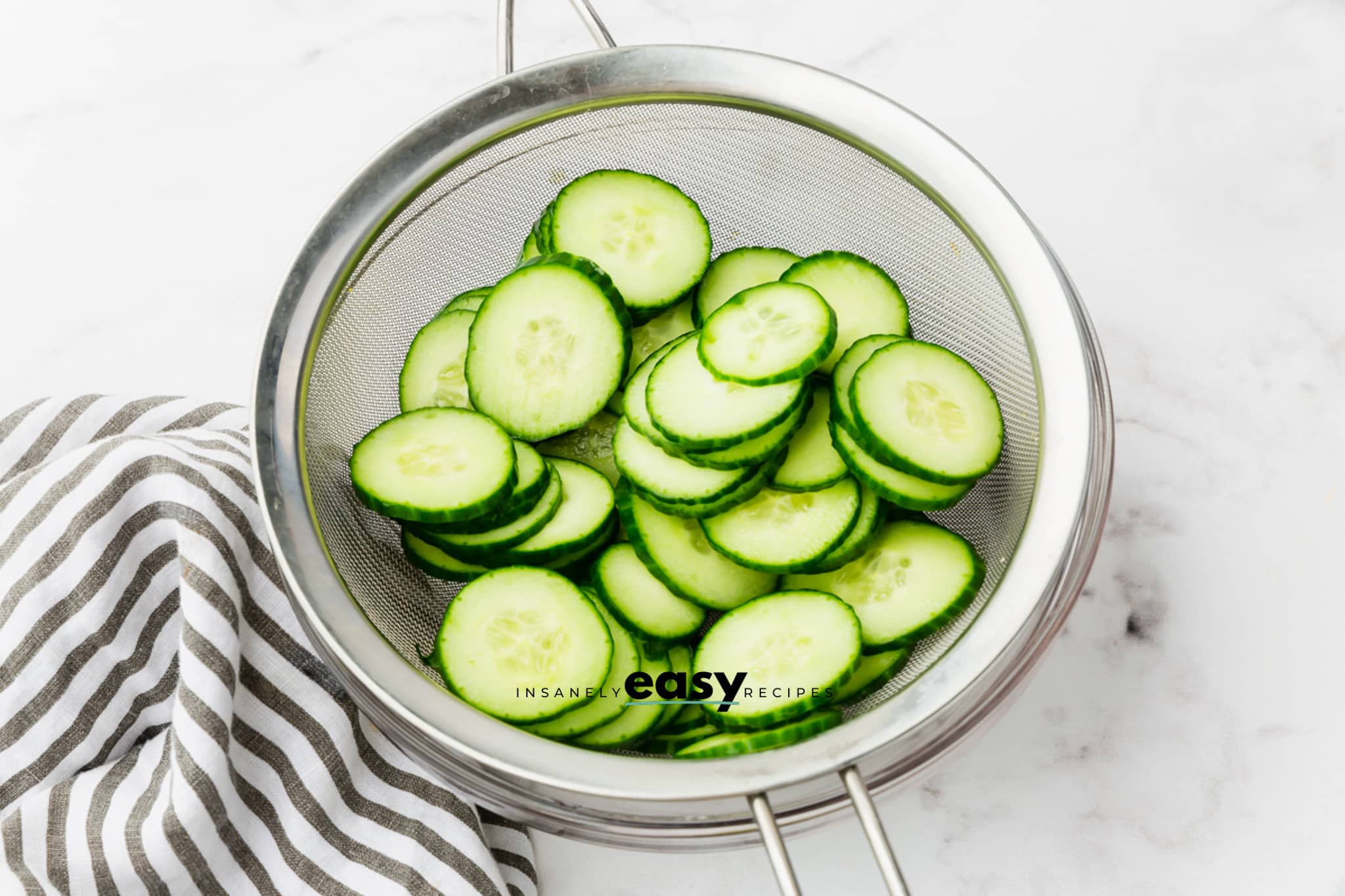 a mesh sieve filled with thinly sliced cucumbers.