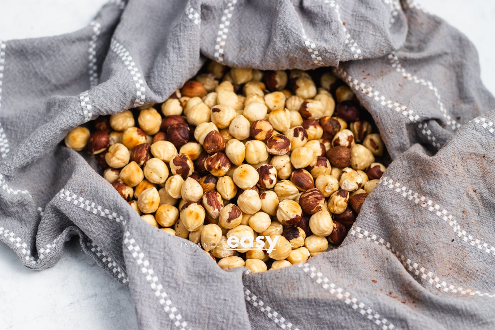 Photo of roasted hazelnuts in a kitchen towel, to rub off the skin of the hazelnut.
