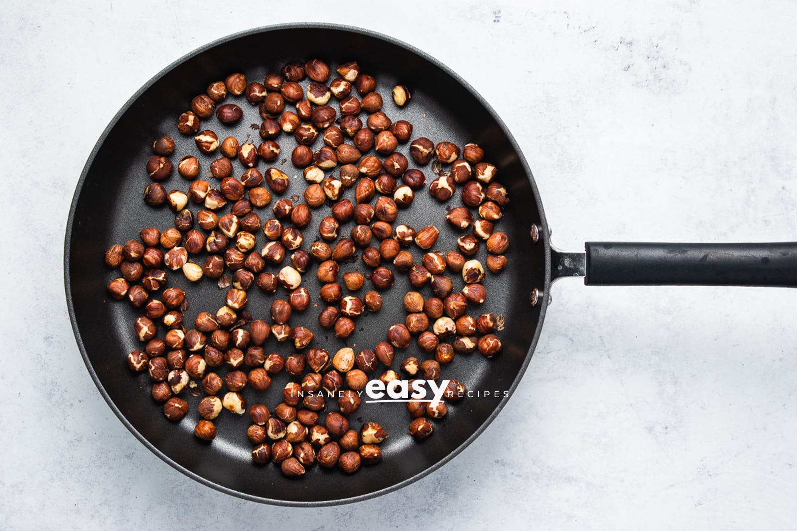 Top view photo of hazelnuts roasting in a saucepan.