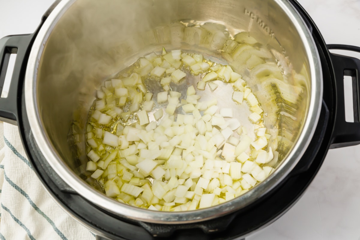 Top view photo of diced onions sautéing in the instant pot until soft.