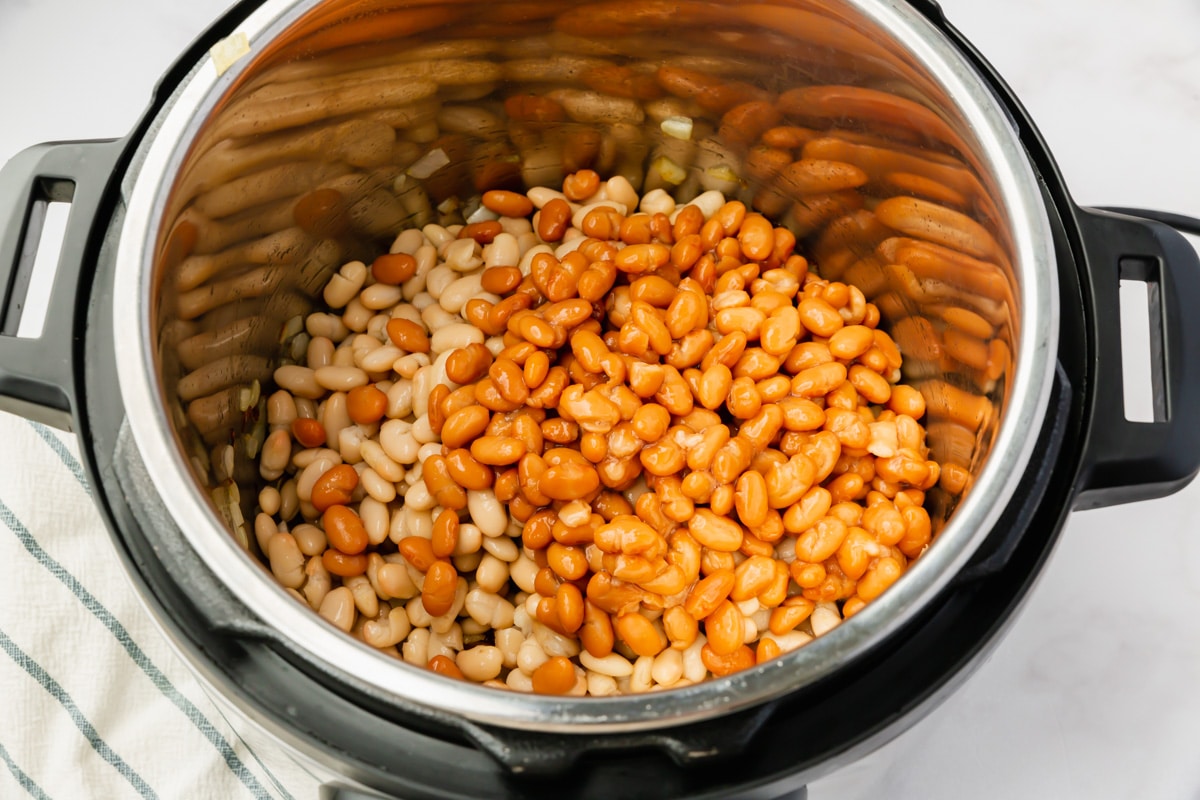 Top view photo of beans added to the instant pot with the diced onions, to make Instant Pot Baked Beans.