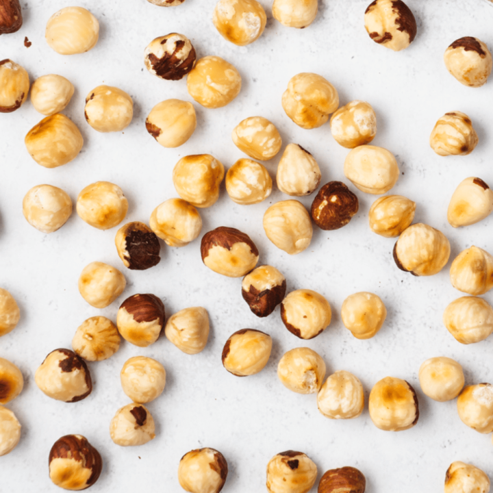 Top view photo of roasted and peeled hazelnuts, spread out over a tabletop surface
