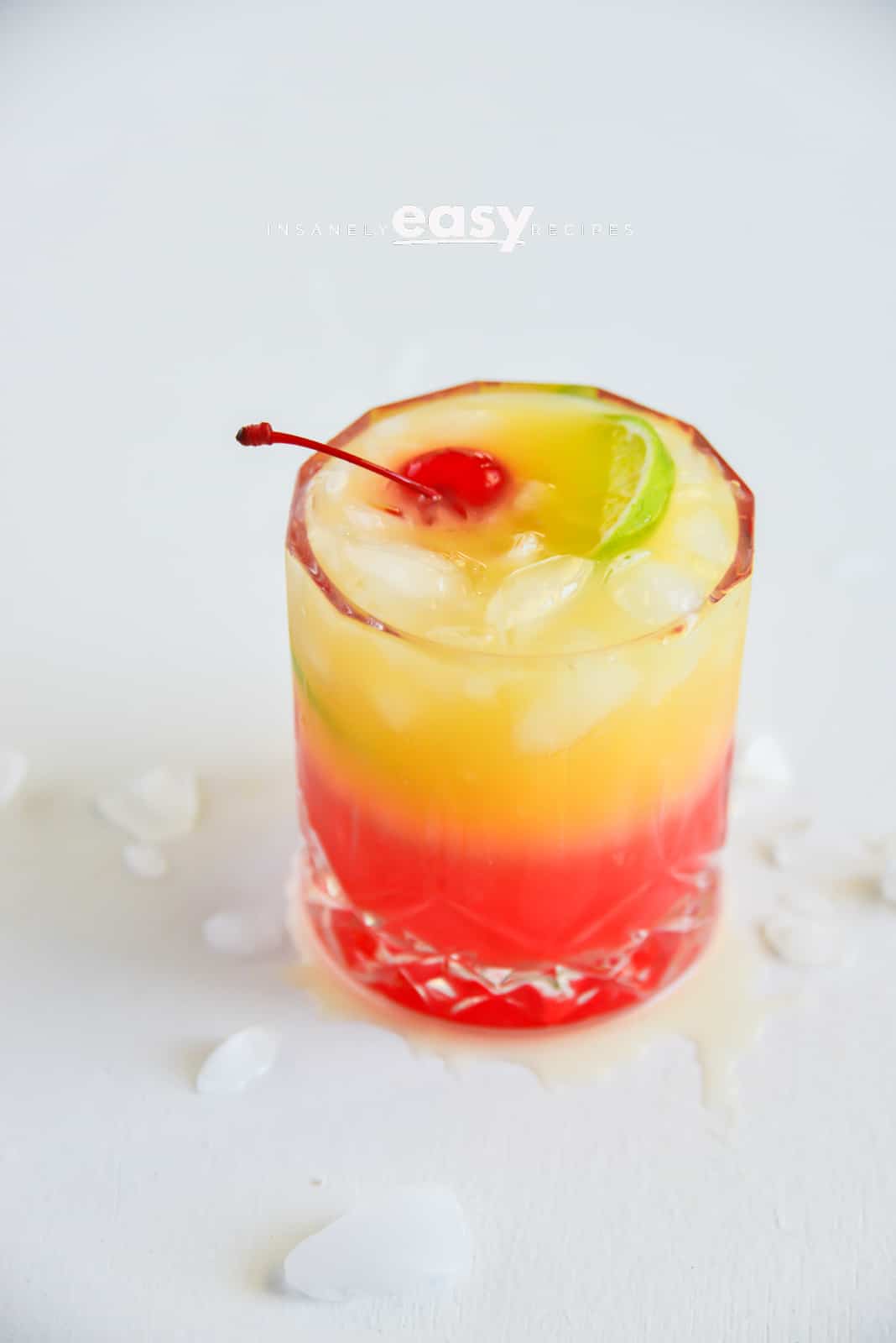 layered malibu rum sunrise drink with a cherry and lime garnish