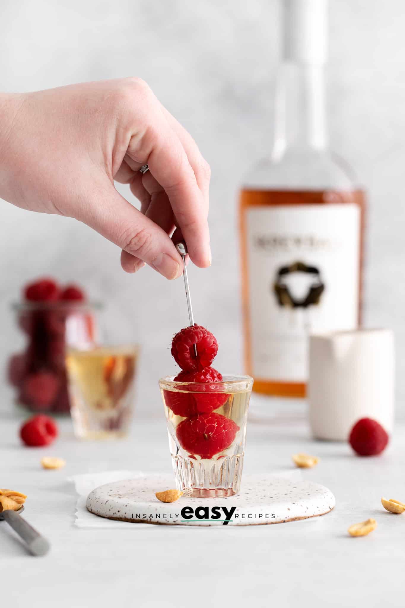 a PBJ shot with a skewer of fresh raspberries in it.