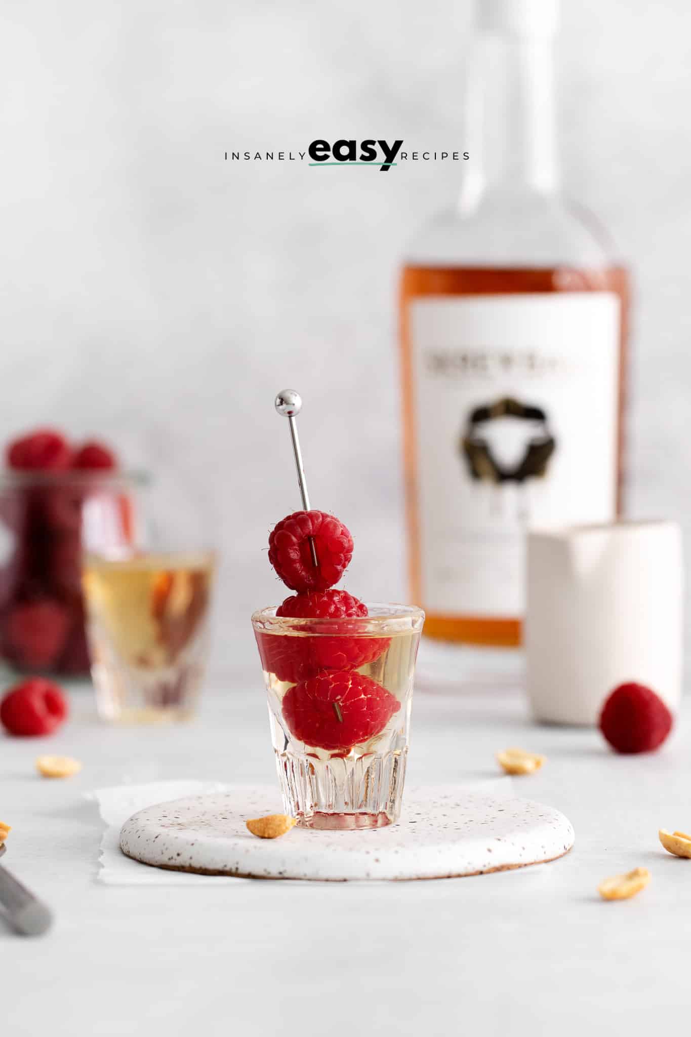a Peanut butter and jelly shot with a skewer of fresh raspberries in it.