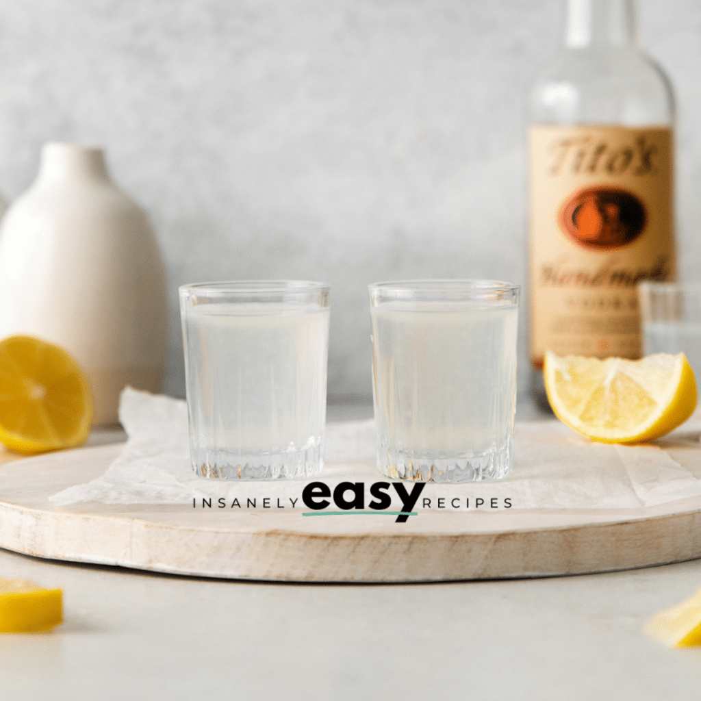 Photo of two White Tea Shots on a wooden platter with lemon wedges around the shots for decoration.