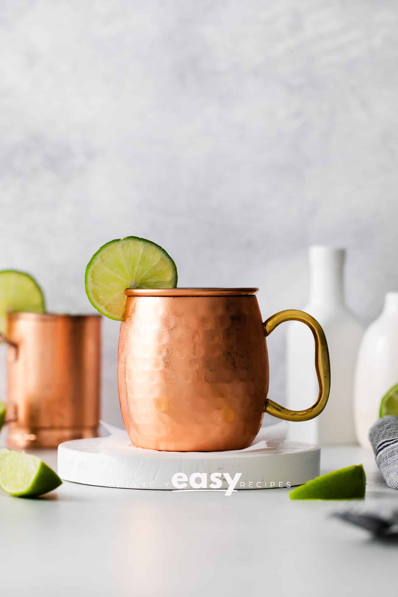 Photo of a London Mule cocktail in a copper mug with a lime round on the rim of the mug. 