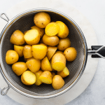 cooked potato halves in metal strainer