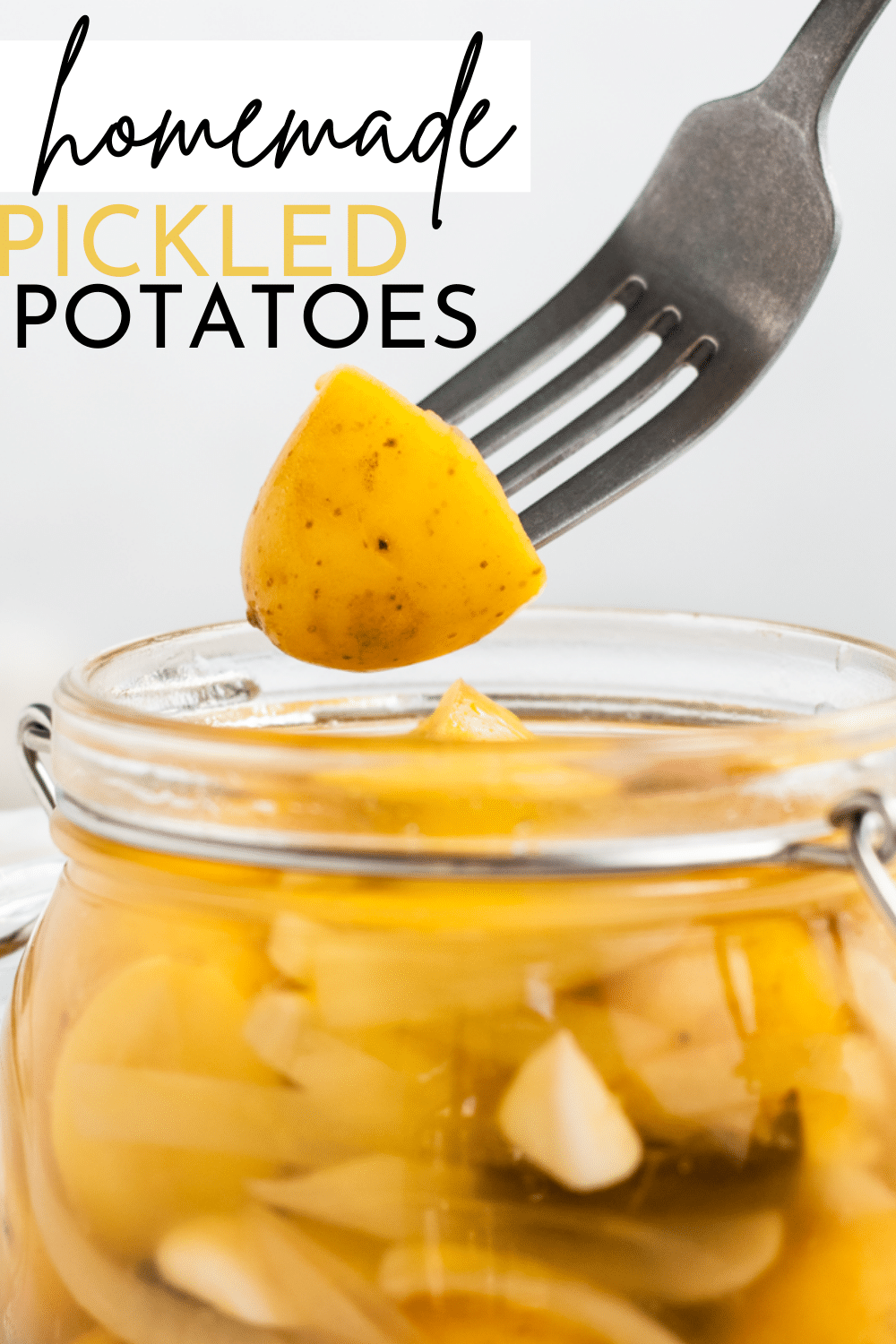 clear glass jar with yellow baby round potatoes cut in half with thin white onion slices in milky liquid. with text overlay, pickled potatoes