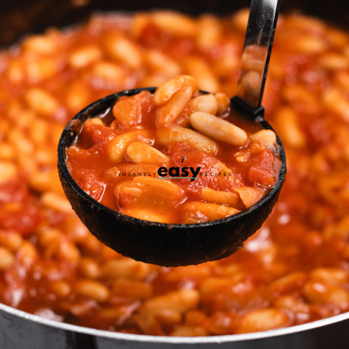 a ladle lifting vegan baked beans out of a pot.