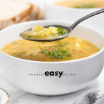 closeup shot of a bowl of simple potato soup. A spoon is holding up a serving.
