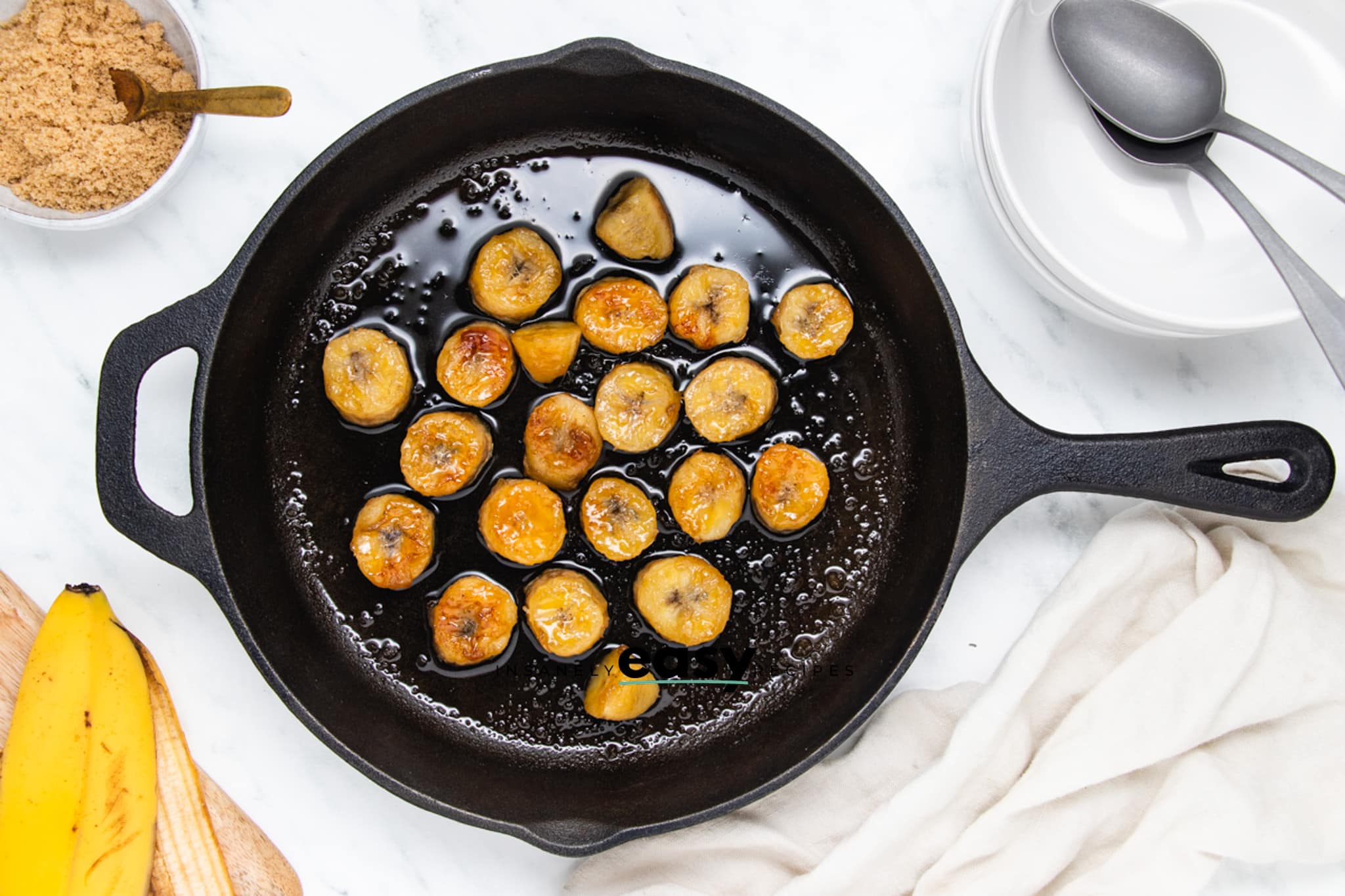Top view photo of bananas in a cast iron skillet, caramelizing in butter.