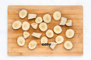 Top view photo of sliced bananas on a wooden cutting board.