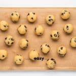 Top view photo of finished No Bake Cookie Dough Bites, on a wooden cutting board and ready to enjoy.